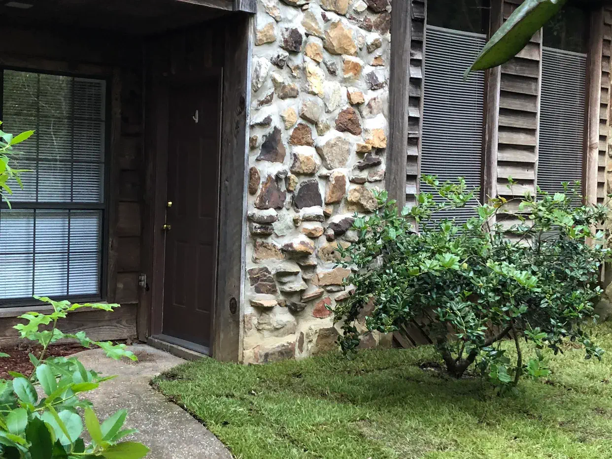 Front walkway leading to a townhome entry with stone facade and tidy landscaping
