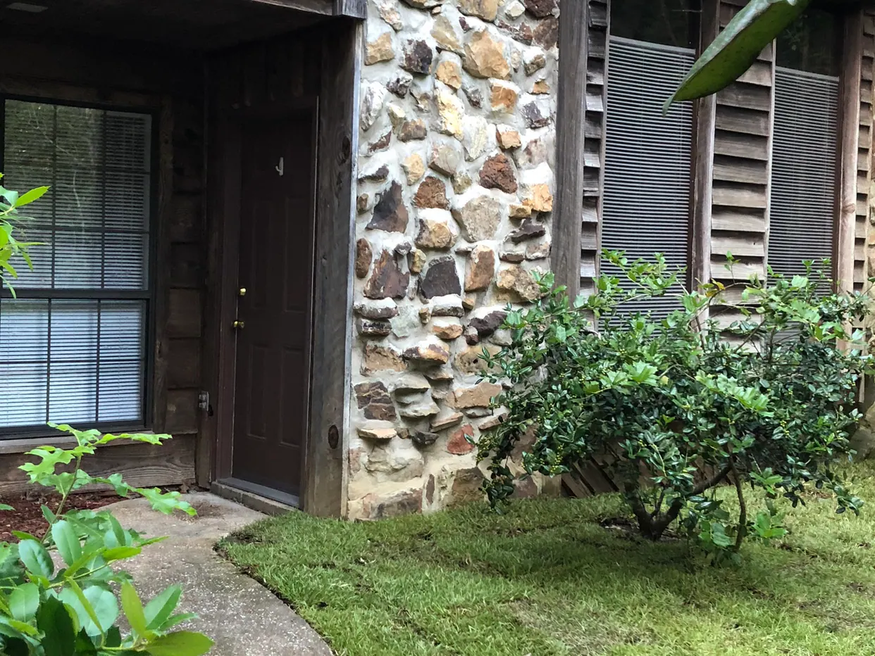 Front walkway leading to a townhome entry with stone facade and tidy landscaping