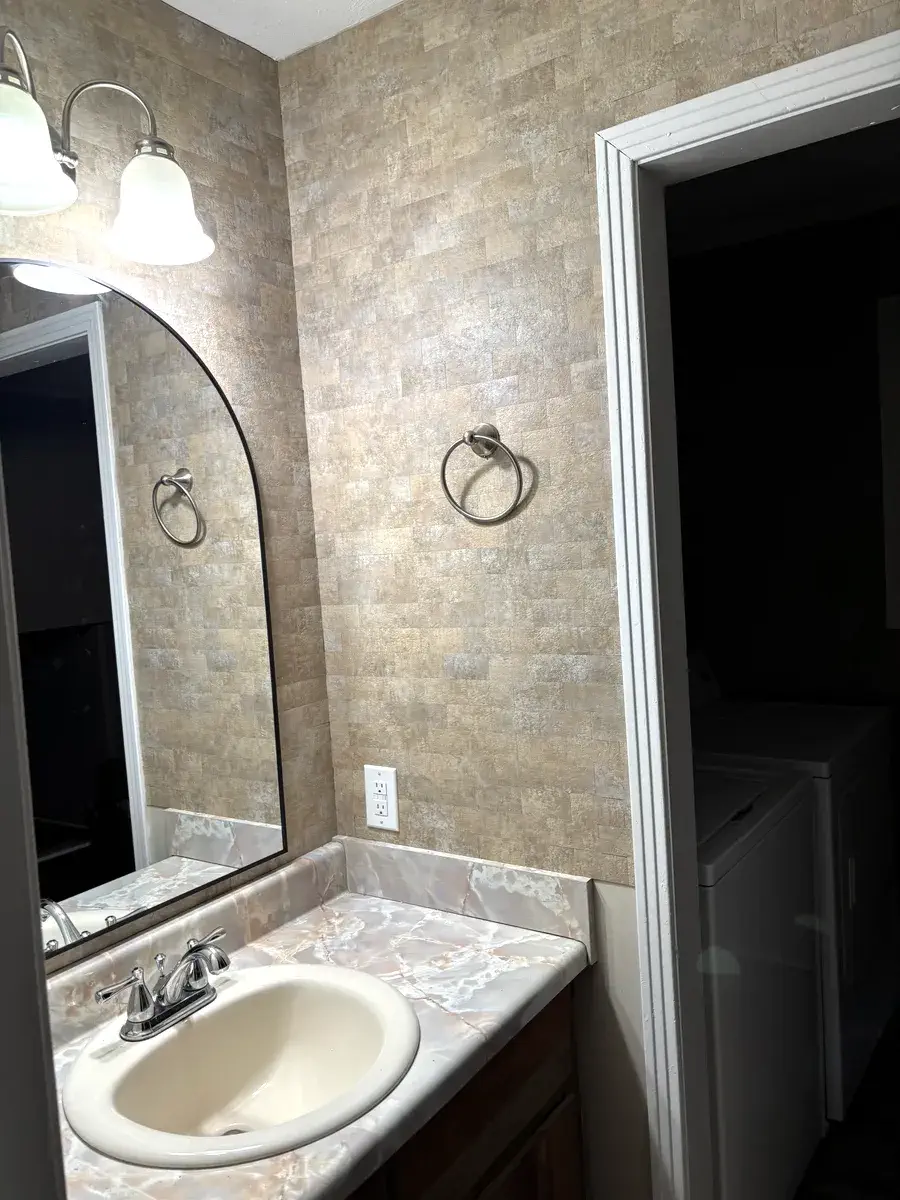 Downstairs half bath with upgraded stone tile and marble-look vanity