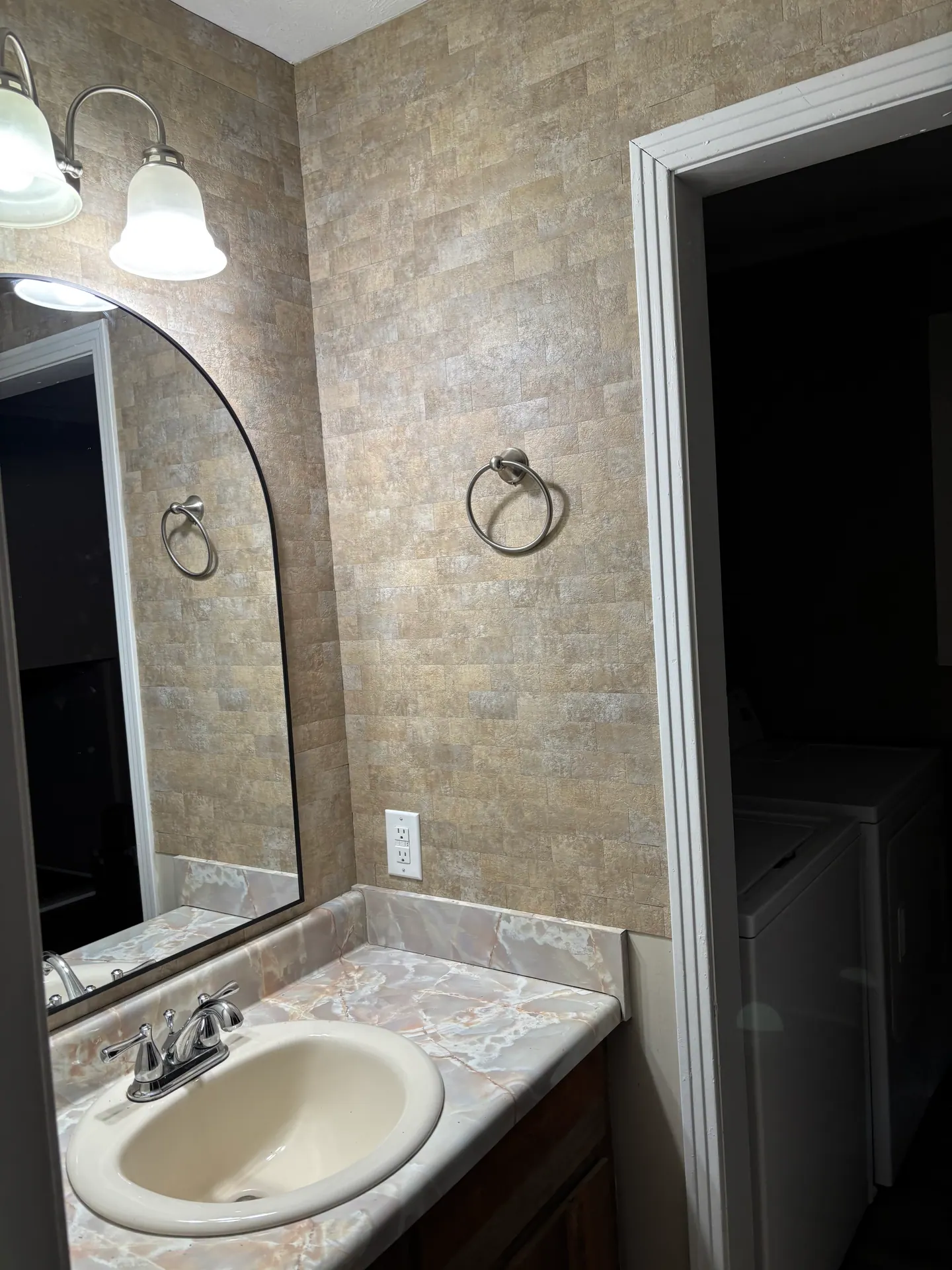 Downstairs half bath with upgraded stone tile and marble-look vanity