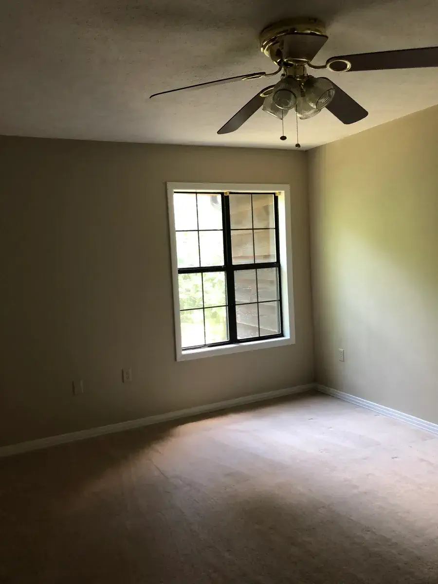 Guest bedroom with a large window and ceiling fan