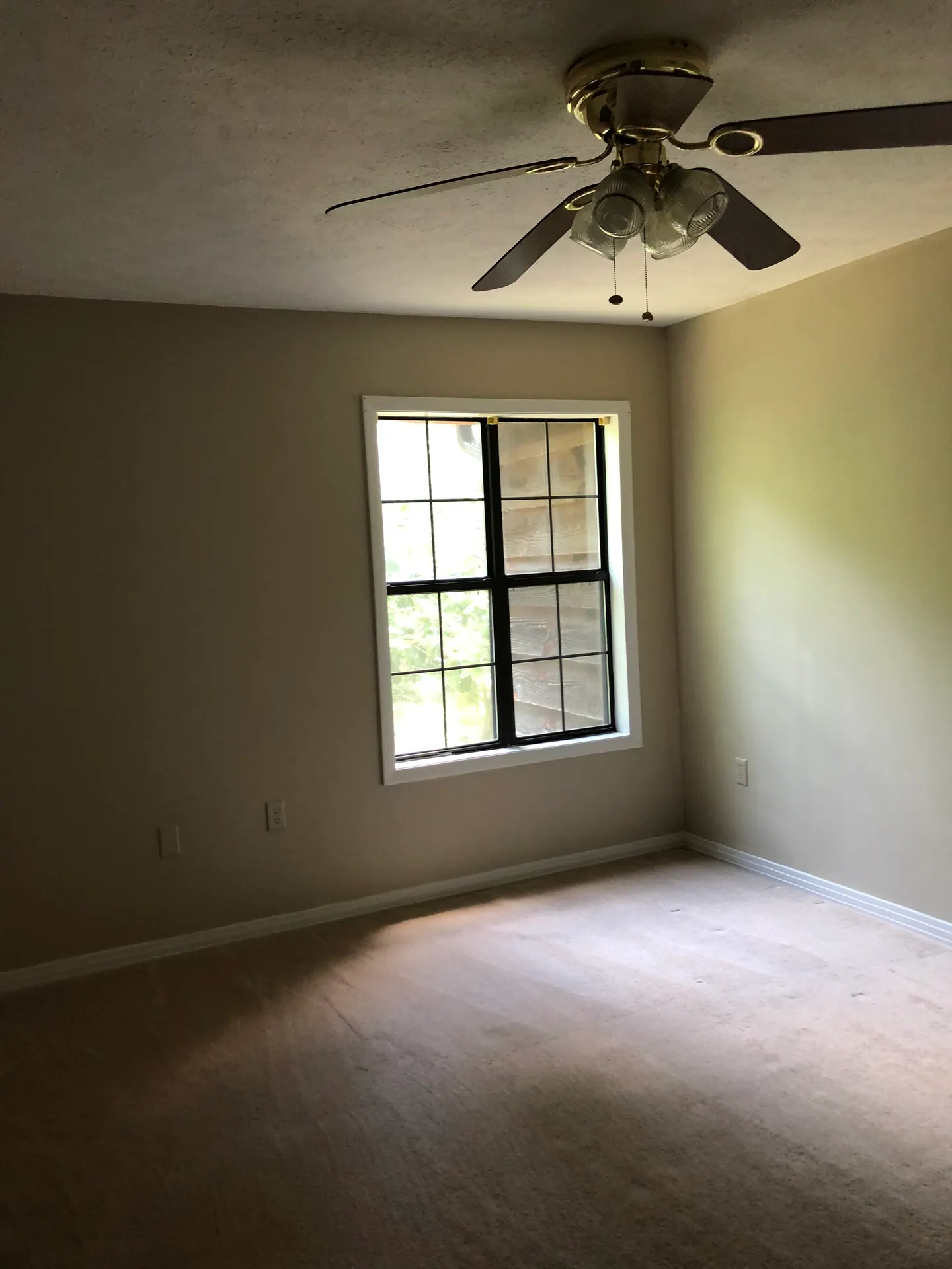 Guest bedroom with a large window and ceiling fan