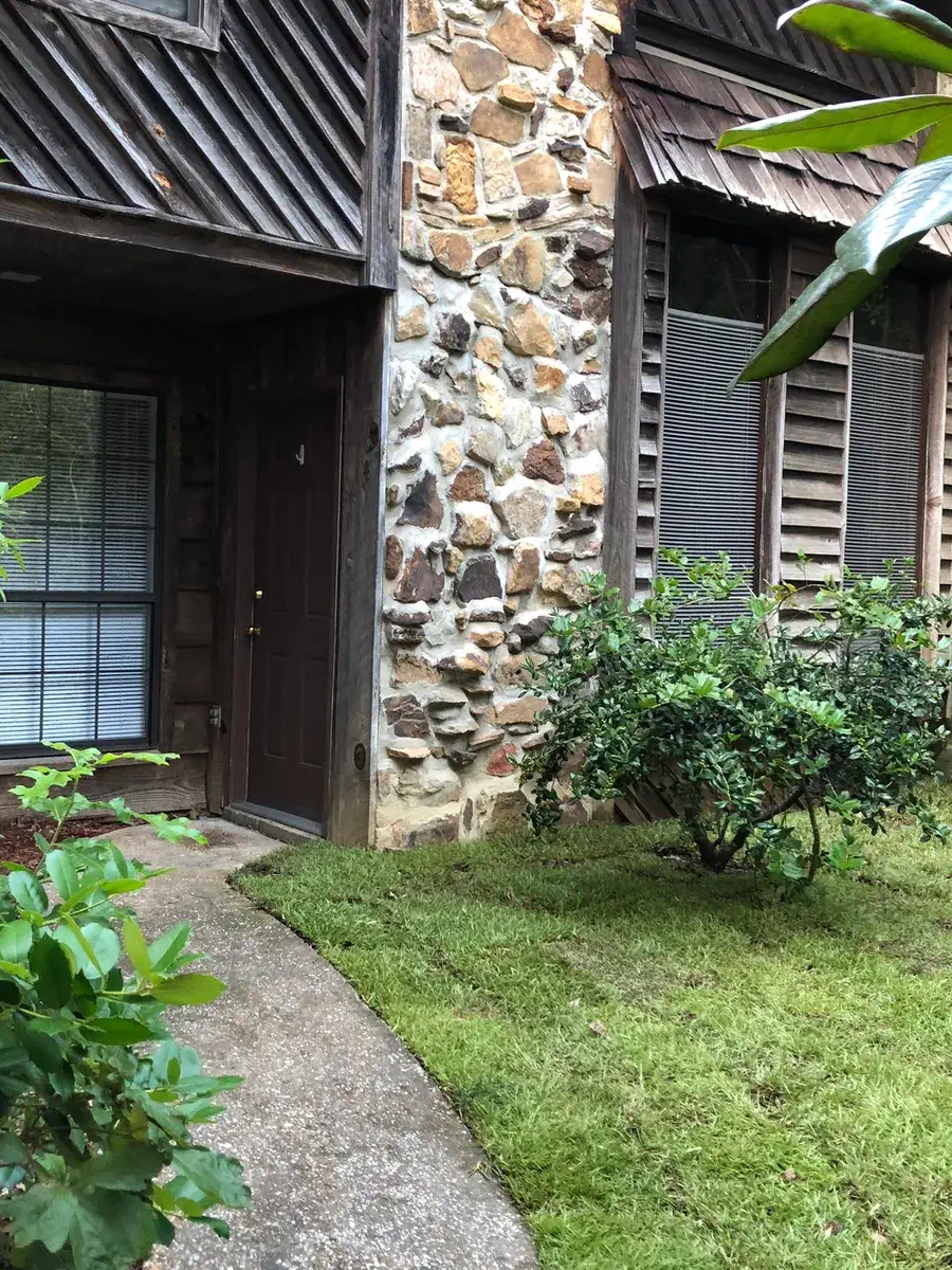 Front walkway and door with stone facade and tidy landscaping