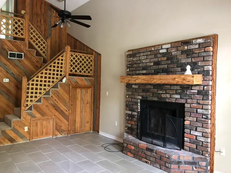 Brick fireplace beside a wood staircase with lattice railing