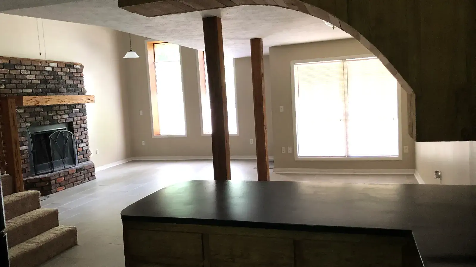 Living room with a brick fireplace, kitchen island, and large windows