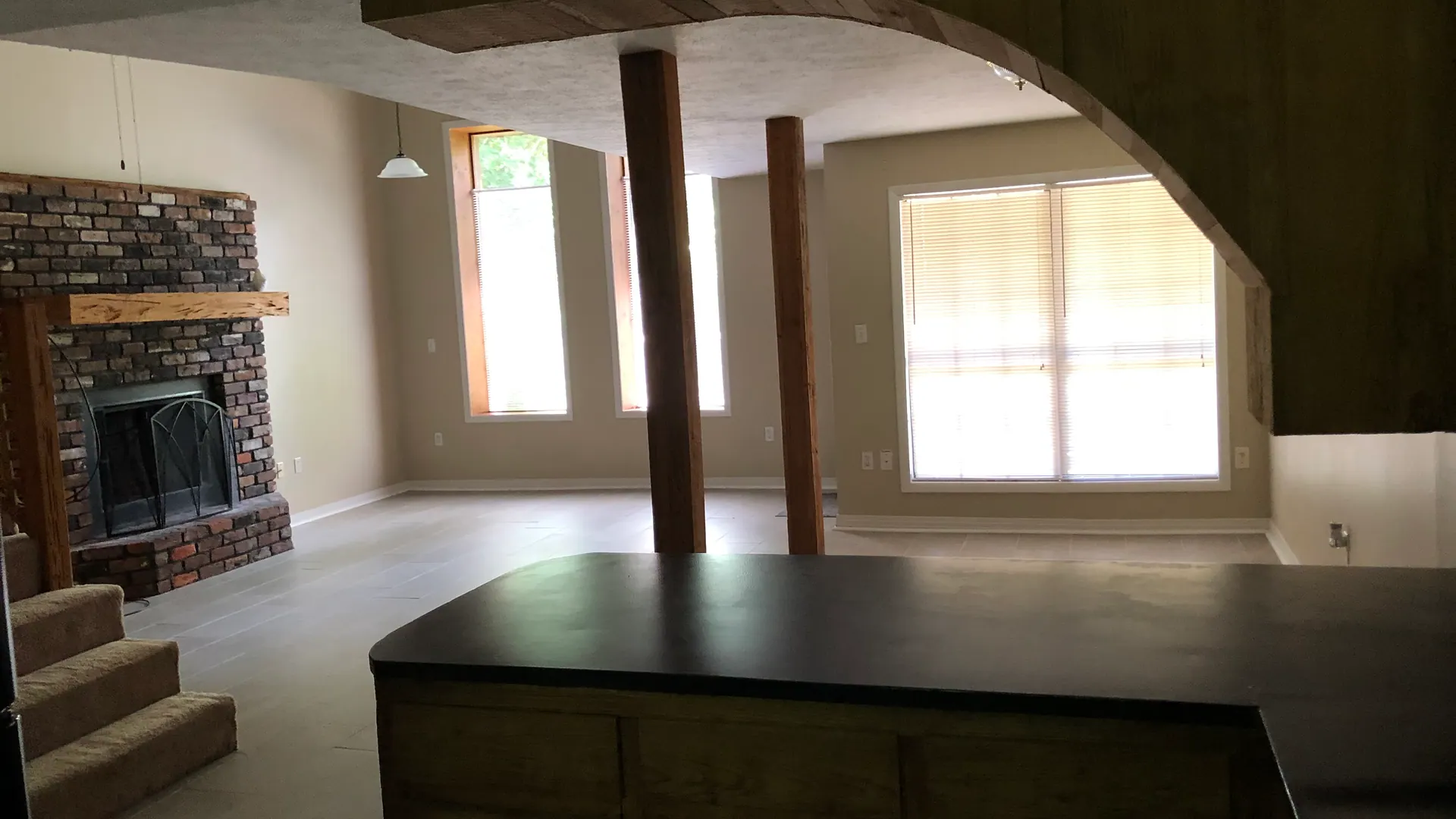 Living room with a brick fireplace, kitchen peninsula, and large windows