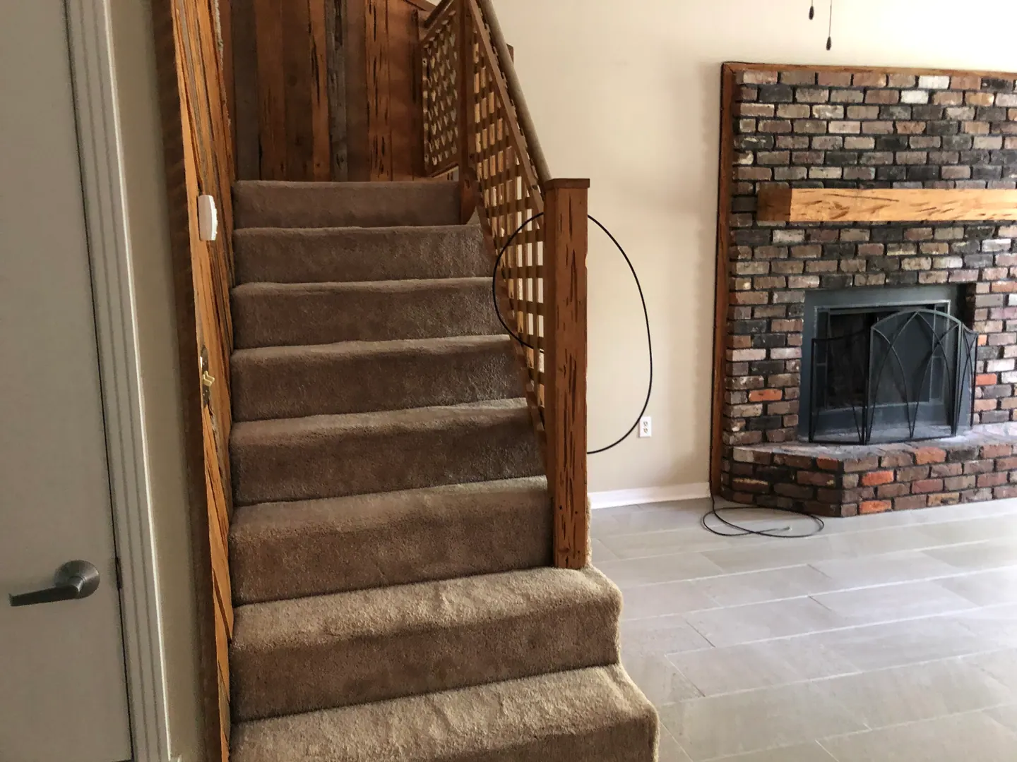 Carpeted stairs with wood railing beside the fireplace